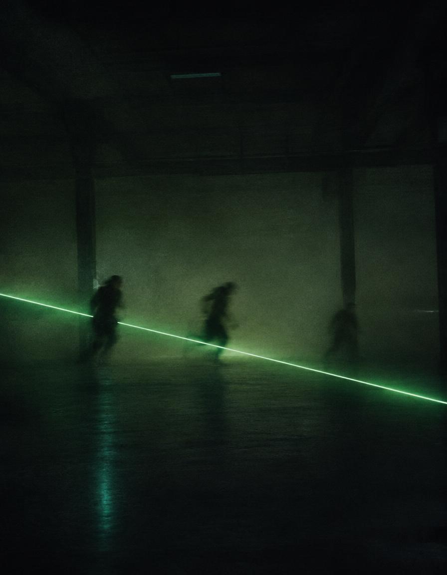 Dancers crossing a laser line in a foggy warehouse